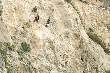 Workers on limestone cliff face completing abseil access work.